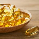 Close up capsules with Vitamin D, E or Omega 3,6,9 fatty acids in bottle on old wooden backgrounds.