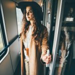 Girl in the brown hats opening the door of train compartment