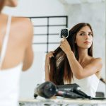 Hairstyle and daily hair care at home. Cheerful millennial caucasian lady combing long hair