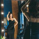 Sexy young woman in elegant cocktail silk black dress dancing and posing in mirror reflection